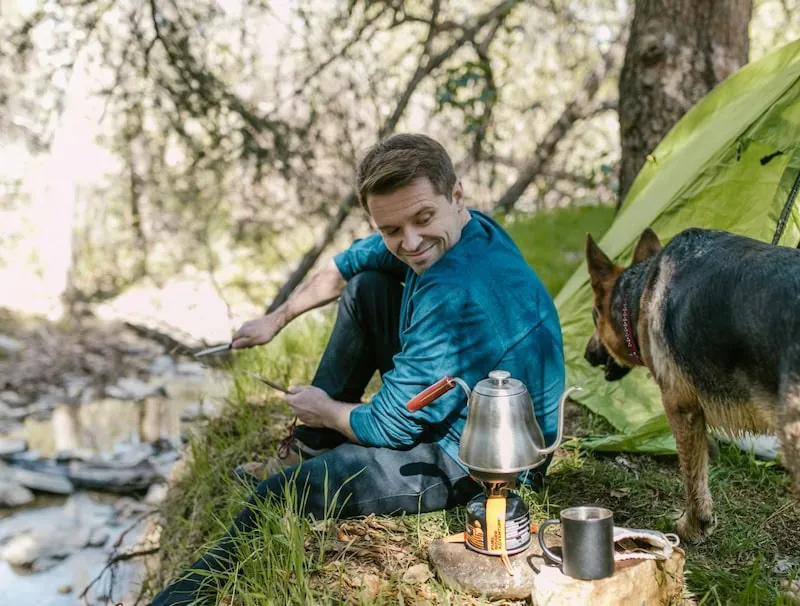 guy in the woods camping with dog